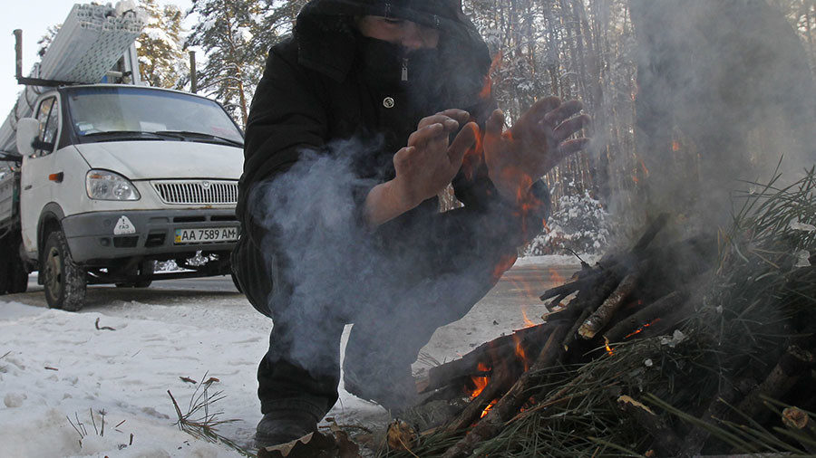 FILE PHOTO: Men make a fire on the roadside to get warm