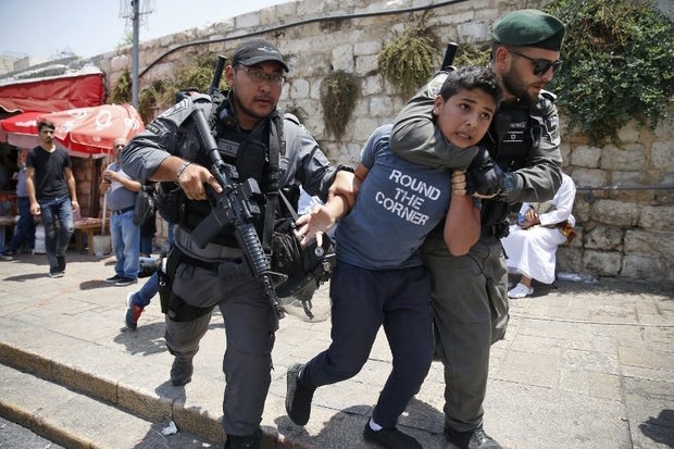 Click to enlarge Israeli border guards detain a Palestinian boy