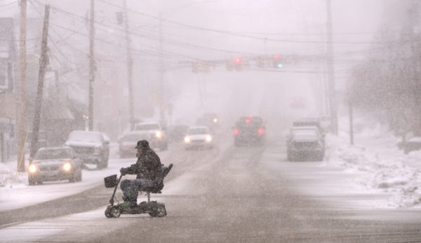 A man rides an electric wheel chair on Union Street as heavy snow started falling in Bangor Tuesday afternoon.