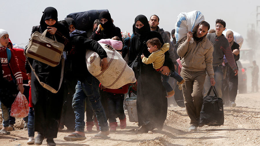 People walk with their belongings as they flee the rebel-held town of Hammouriyeh