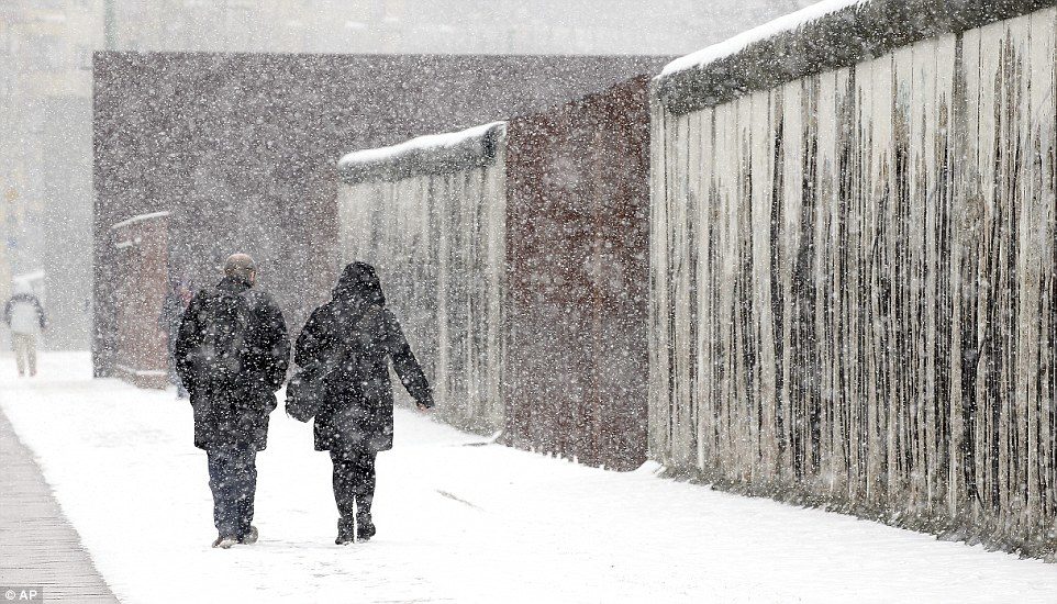 Click to enlarge Berlin was particularly badly affected by the snow on Tuesday, with most of the city receiving a thick coating. Here a man and a woman walk alongside a section of the Berlin as the flakes fall
