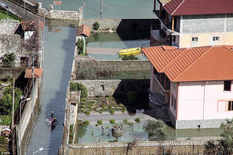 Click to enlarge An Albanian man rides on his bicycle in the flooded roads of Ajazem village near Shkoder, after the country was hit by heavy rainfall and melting snow