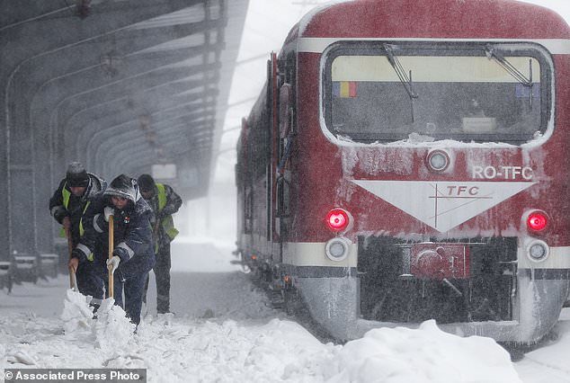 Municipal workers clear ice and snow from the platforms of the Gara de Nord, the main railway station in Bucharest, Romania, Friday, March 23, 2018.
