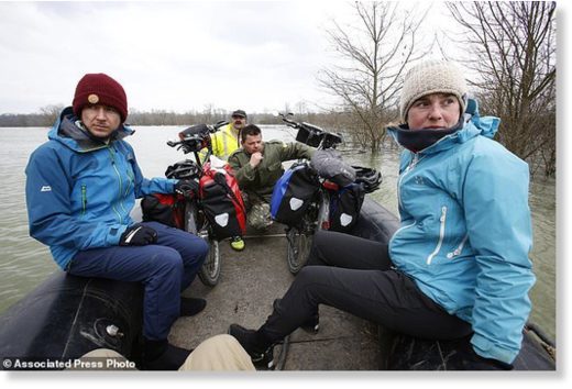 Click to enlarge Bosnian Bosko Savic, centre, transporting two Ausrian tourists with their bikes from Austria who had been trapped by rising water in the village of Bistrica near Gradiska, 260 kms northwest of the Bosnian capital of Sarajevo, Thursday, March 22, 2018.