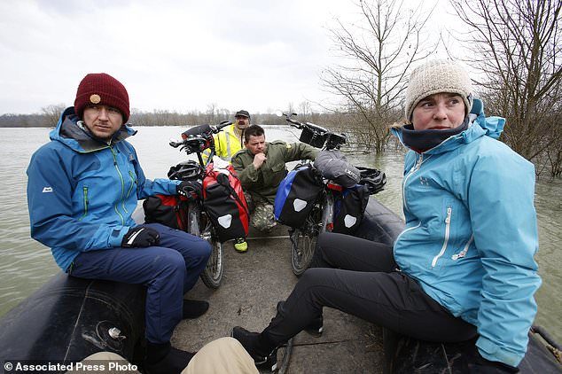 Bosnian Bosko Savic, centre, transporting two Ausrian tourists with their bikes from Austria who had been trapped by rising water in the village of Bistrica near Gradiska, 260 kms northwest of the Bosnian capital of Sarajevo, Thursday, March 22, 2018.