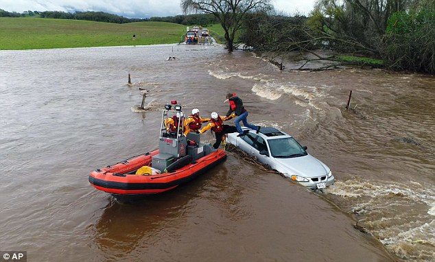 Click to enlarge Firefighters help a motorist whose car became engulfed in the deep floodwater in Folsom