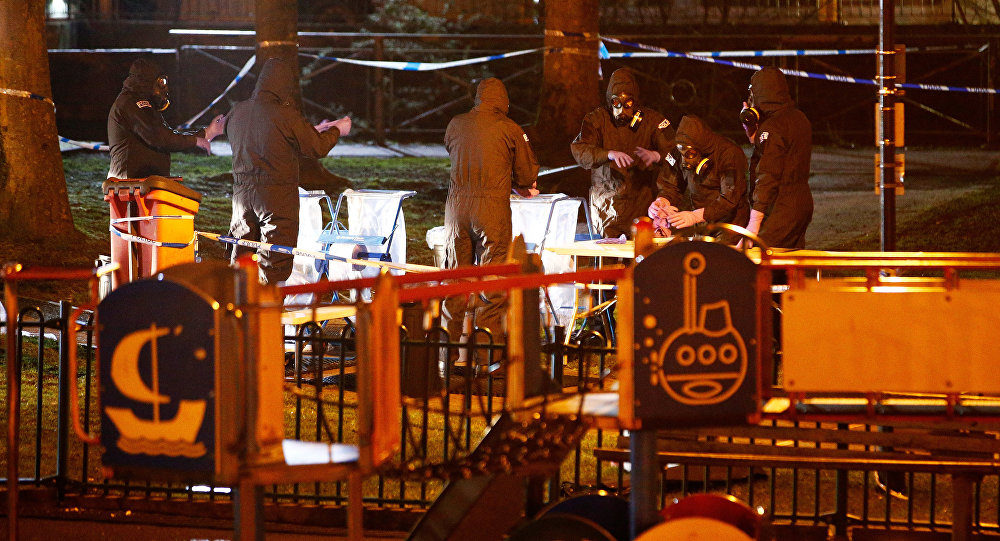 Click to enlarge Members of the emergency services wearing protective clothing work next to a children's play area