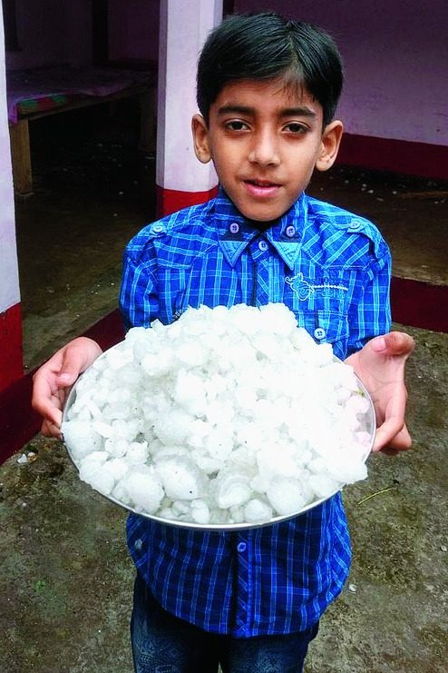 A boy shows the hailstones in Sitamarhi