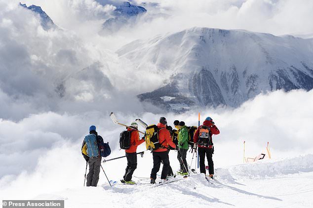 Rescuers stand near the avalanche site