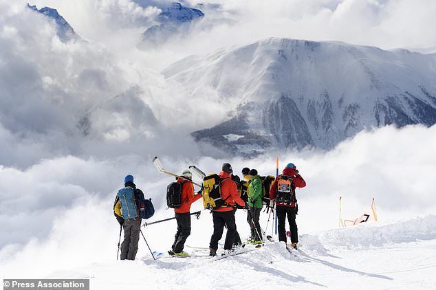Click to enlarge Rescuers stand near the avalanche site