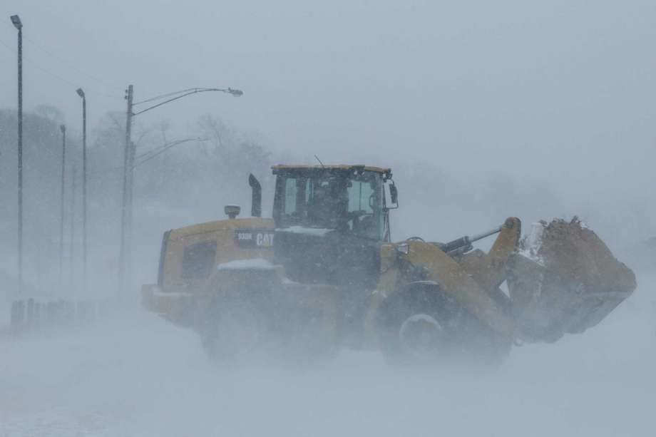 A loader moves sand from a parking lot back to Pere Marquette Beach in Muskegon, Mich.