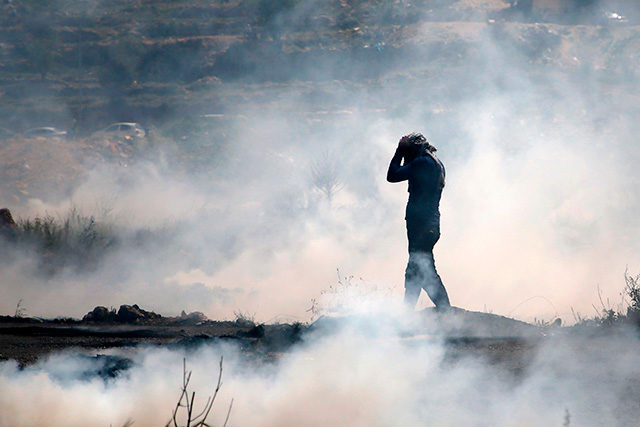 A Palestinian man wears a gas mask