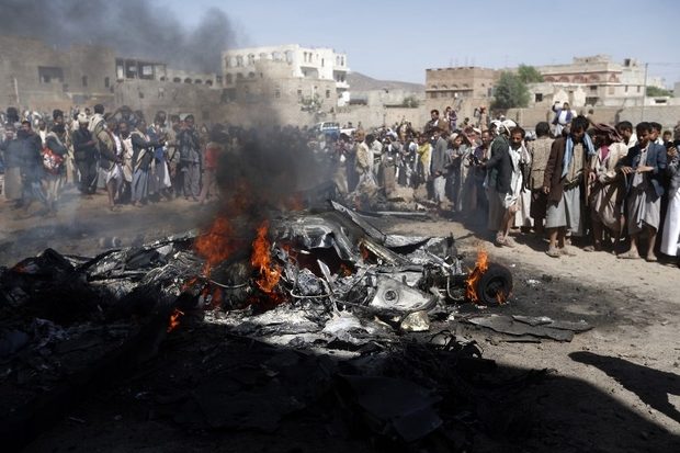 Yemenis gather around the burning wreckage of a drone in the capital Sanaa on 1 October 2017