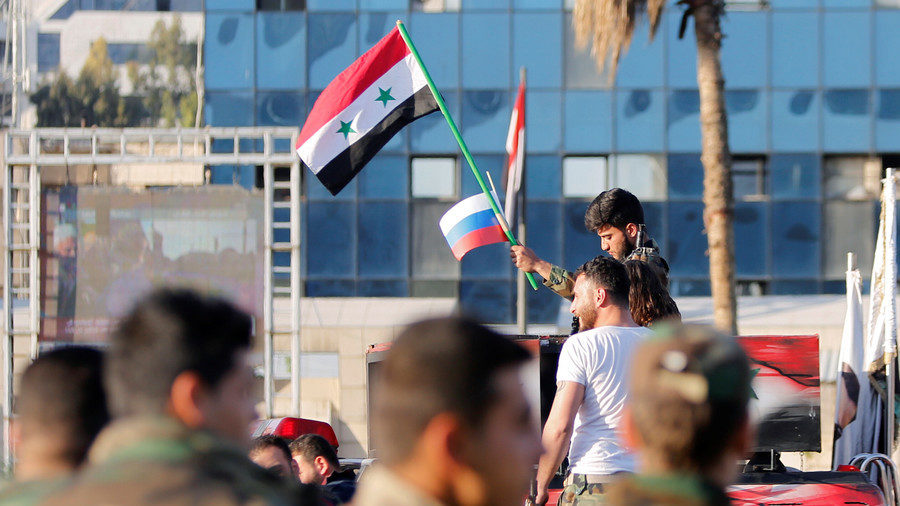 Click to enlarge A Syrian soldier waves Russian and Syrian flags during a protest against air strikes in Damascus,Syria April 14,2018