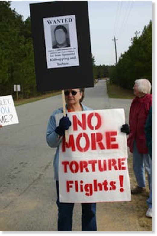Click to enlarge A woman holding anti-torture signs