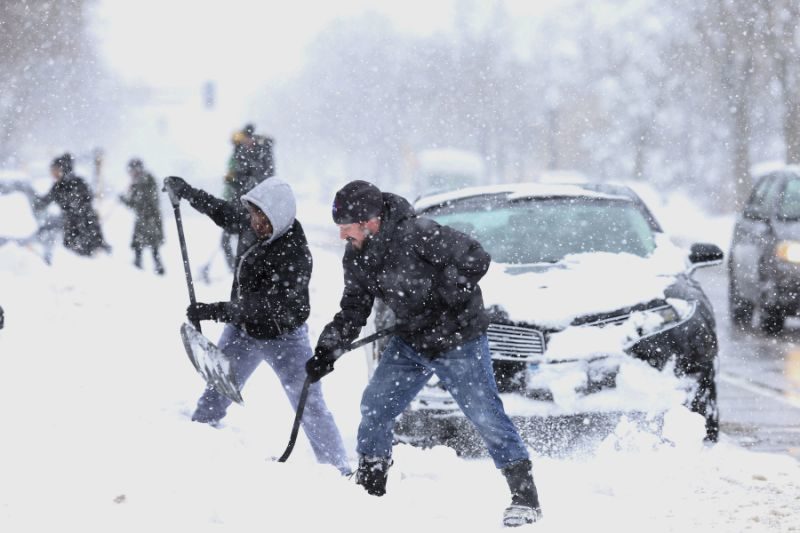 Neighbors John Bauer, right, and Fahmi Osman help residents dig their vehicles out of the snow after Saturdays blizzard, in Minneapolis, Minn., Sunday, April 15, 2018.