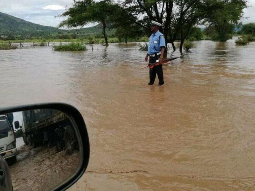 Police Constable Abdi Galgalo of Sultan Hamud Police Station captured by a motorist while directing traffic on a flooded section of the Nairobi-Mombasa highway at Sultan Hamud on Saturday.