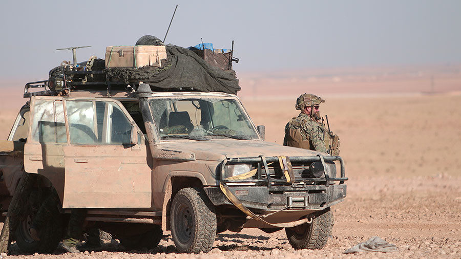 A US fighter stands near a military vehicle