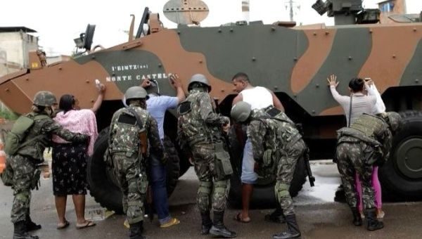 Click to enlarge Security forces search residents of the Manguinhos favela complex.