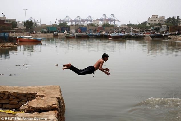 A boy jumps into the water to cool off during hot and humid weather