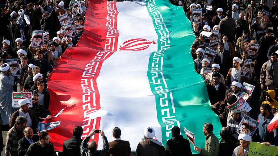 Click to enlarge Pro-government demonstrators wave their national flag during a march in the Iranian city of Qom on January 3, 2018