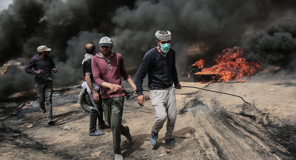 Palestinian protesters pull on a burning tire during clashes with the Israeli forces