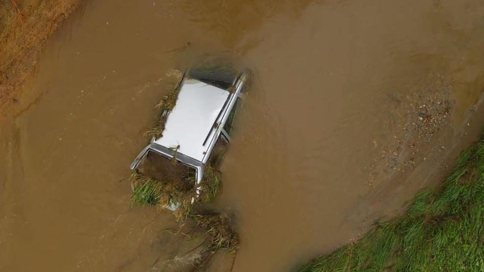 A car is submerged in grassy, muddy rain water in Frederick following days of heavy rain.