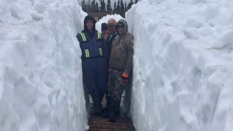 Staff at Igloo Lake Lodge stand amid six-foot-tall snowbanks that encompass the Labrador fishing camp on June 13.