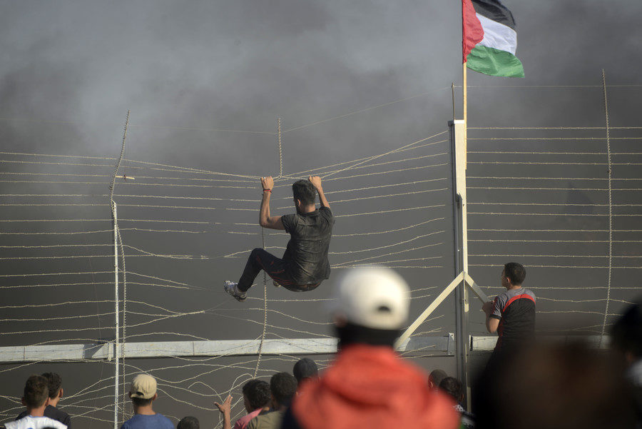 Protester hanging on the fence at Gaza border