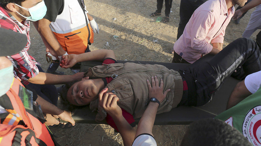 Palestinians carry a protester injured by Israeli forces at the Gaza border