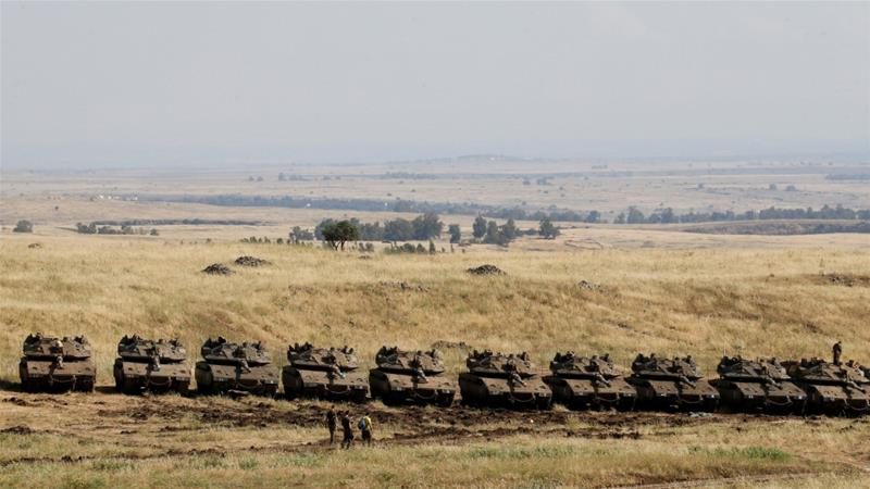Click to enlarge Israeli soldiers walk past tanks