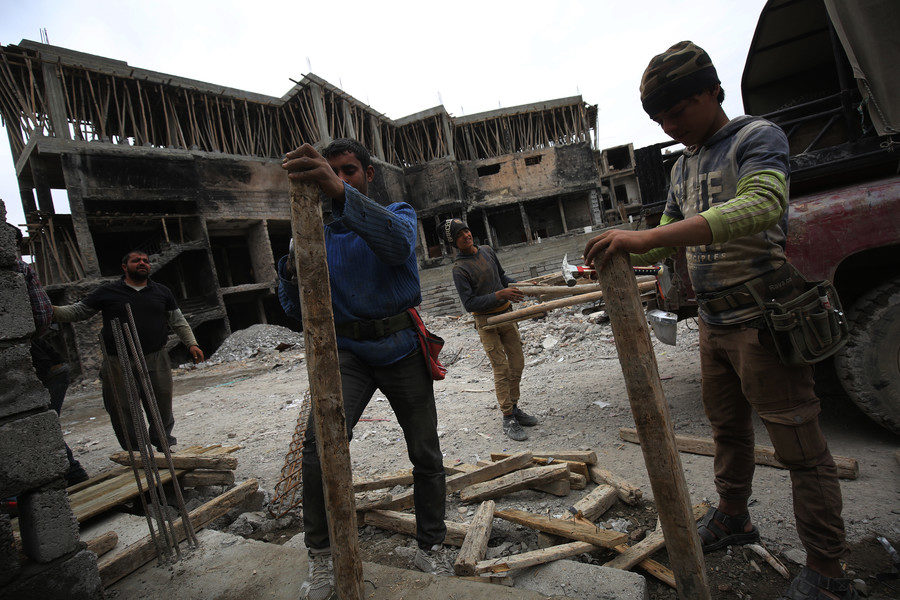 Click to enlarge Iraqi workers repair a building in Mosul on March 15, 2018