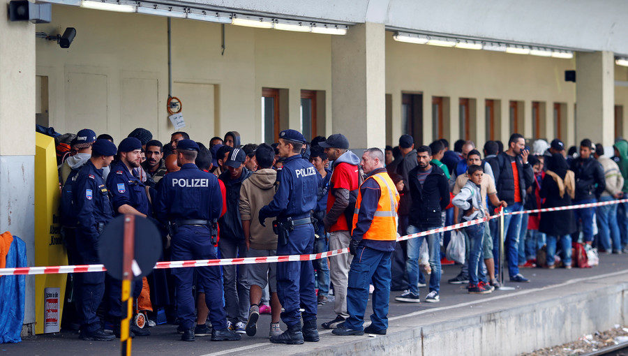 Police in Vienna watch as migrants wait for trains towards Germany