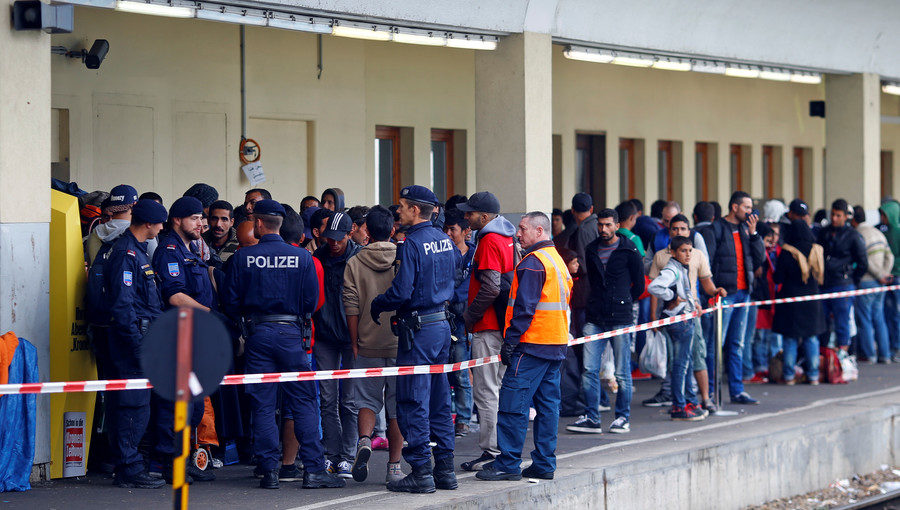 Click to enlarge Police in Vienna watch as migrants wait for trains towards Germany