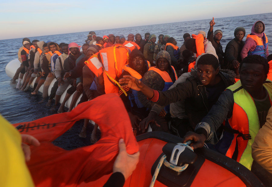 Life jackets are handed to migrants during a search and rescue operation near Libya