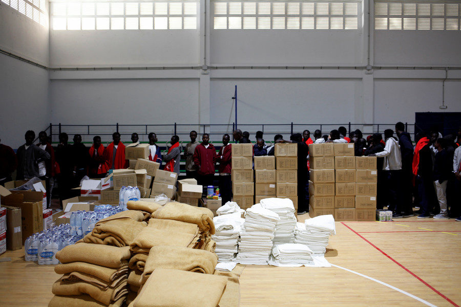 Click to enlarge Migrants wait to be identified by Spanish civil guards