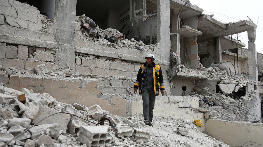 White Helmets member walks on the rubble of destroyed buildings in Eastern Ghouta