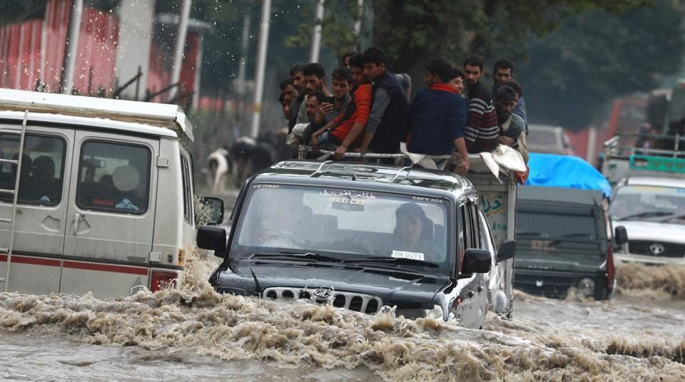 Vehicles wade through a flooded road after heavy rainfall in Srinagar on June 30.