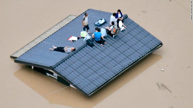 Click to enlarge People wait to be rescued on the roof of a house in Kurashiki, Okayama prefecture.