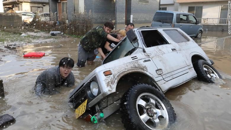 Click to enlarge Residents try to upright a vehicle stuck in a flood hit area in Kurashiki, Okayama prefecture on July 9, 2018.