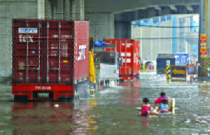 Children play on a flooded street in Quezon City on Tuesday morning, as many communities in Metro Manila awoke to water-logged streets from rains brought by Typhoon Henry, aggravating the southwest monsoon.
