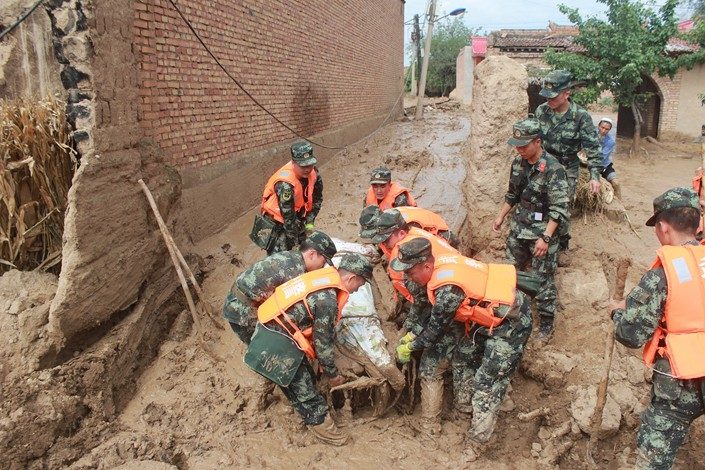 Click to enlarge Armed police officers rescue a victim of a flash flood on Thursday in Linxia prefecture in China’s northwestern province of Gansu