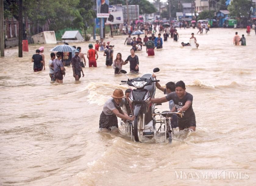 Click to enlarge People in Bago Region wade through floodwater as they move to higher ground. The Department of Meteorology and Hydrology warns of more rain this week