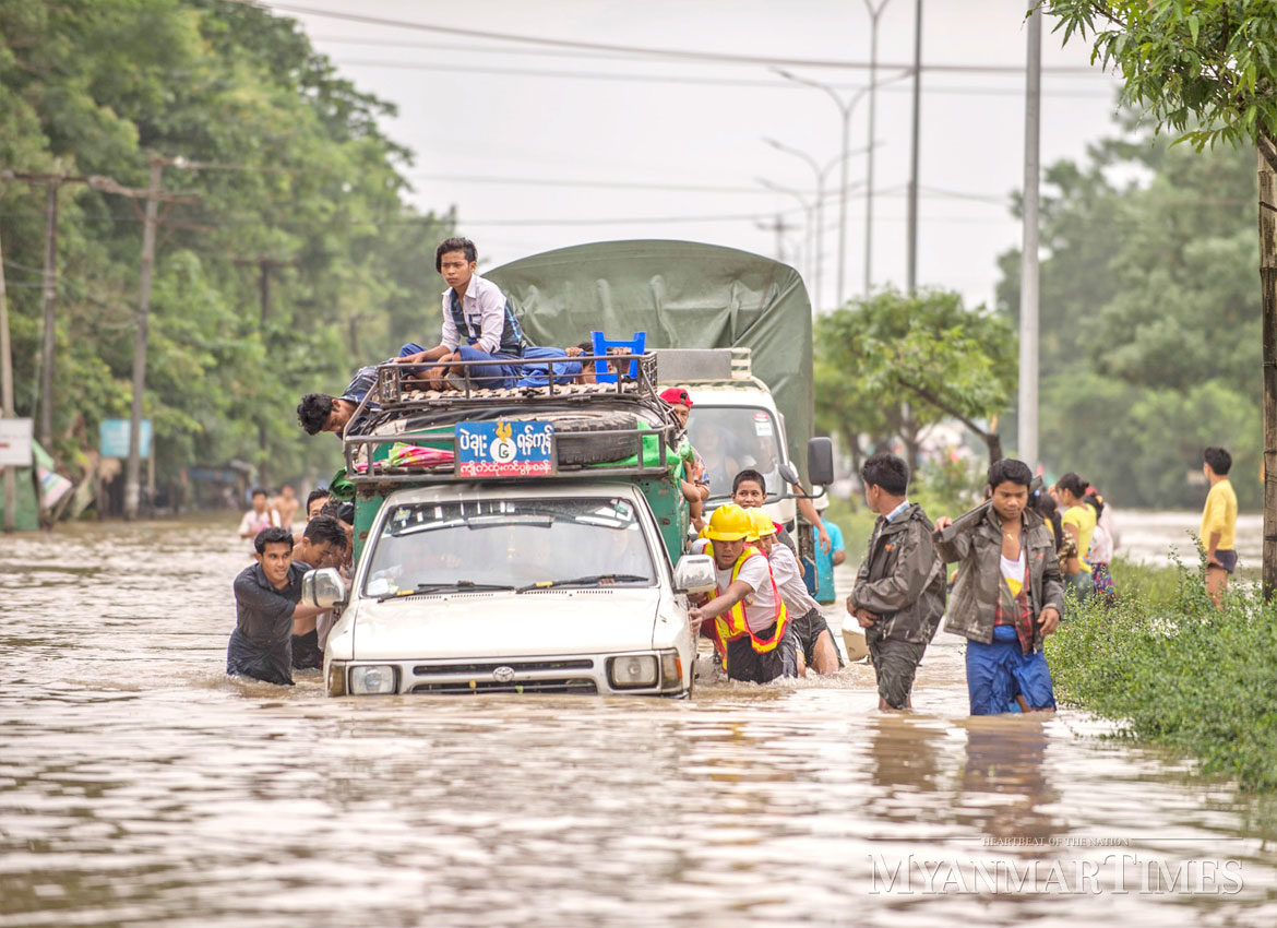 Click to enlarge People help push a stalled truck in Bago on Saturday.