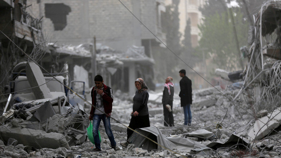 People walk through debris in the ruins of Afrin, Syria