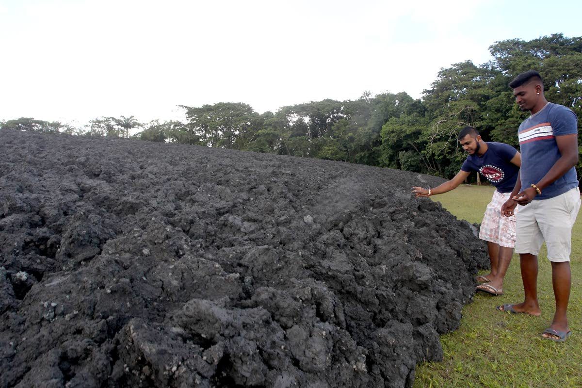 Hindustan villagers Richard Bissoon and Yoge Deochan, right, near the sea of mud left behind after the mud volcano at Devil’s woodyard erupted on Carnival Tuesday.