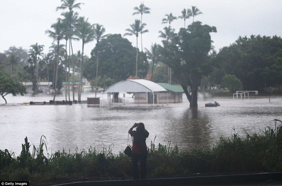 Click to enlarge Pictured is a woman taking photos of floodwaters from Lane on the Big Island on Thursday