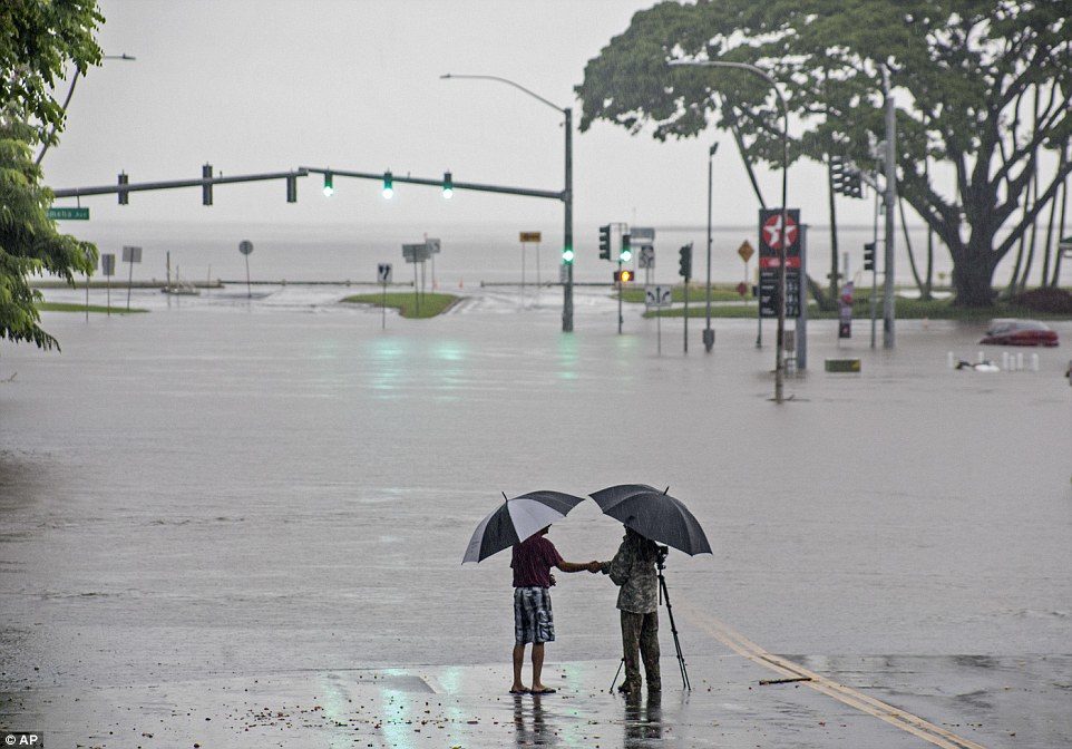 People stand near flood waters from Lane making the intersection of Kamehameha Avenue and Pauahi Street impassable