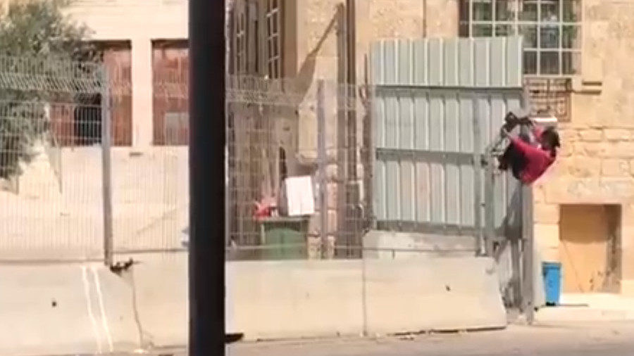 Palestinian girl climbing a closed security gate