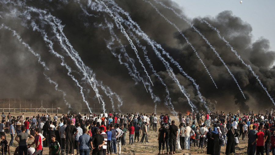 Tear gas canisters, fired by Israeli forces, fall onto Palestinian protesters